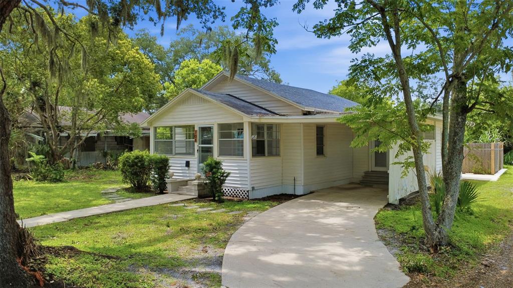 A white, single-story house with a front porch, carport, and concrete driveway sits on grass — 708 CELERY AVENUE, SANFORD, FL