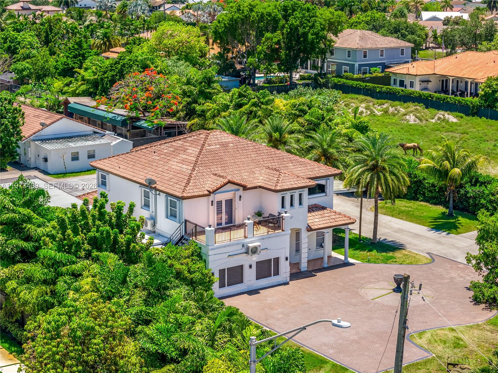 An aerial view shows a two-story house with a tiled roof and a paved driveway — 13050 SW 26th St, Miami FL 33175, MIAMI, FL