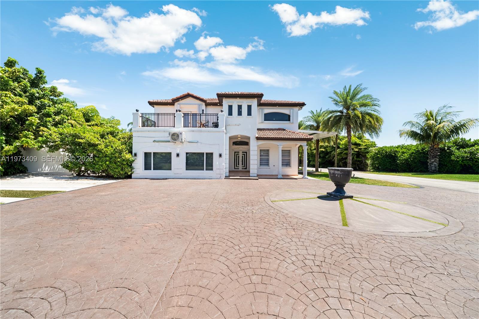 A two-story white stucco house features a large paved driveway and a decorative stone urn — 13050 SW 26th St, Miami FL 33175, MIAMI, FL