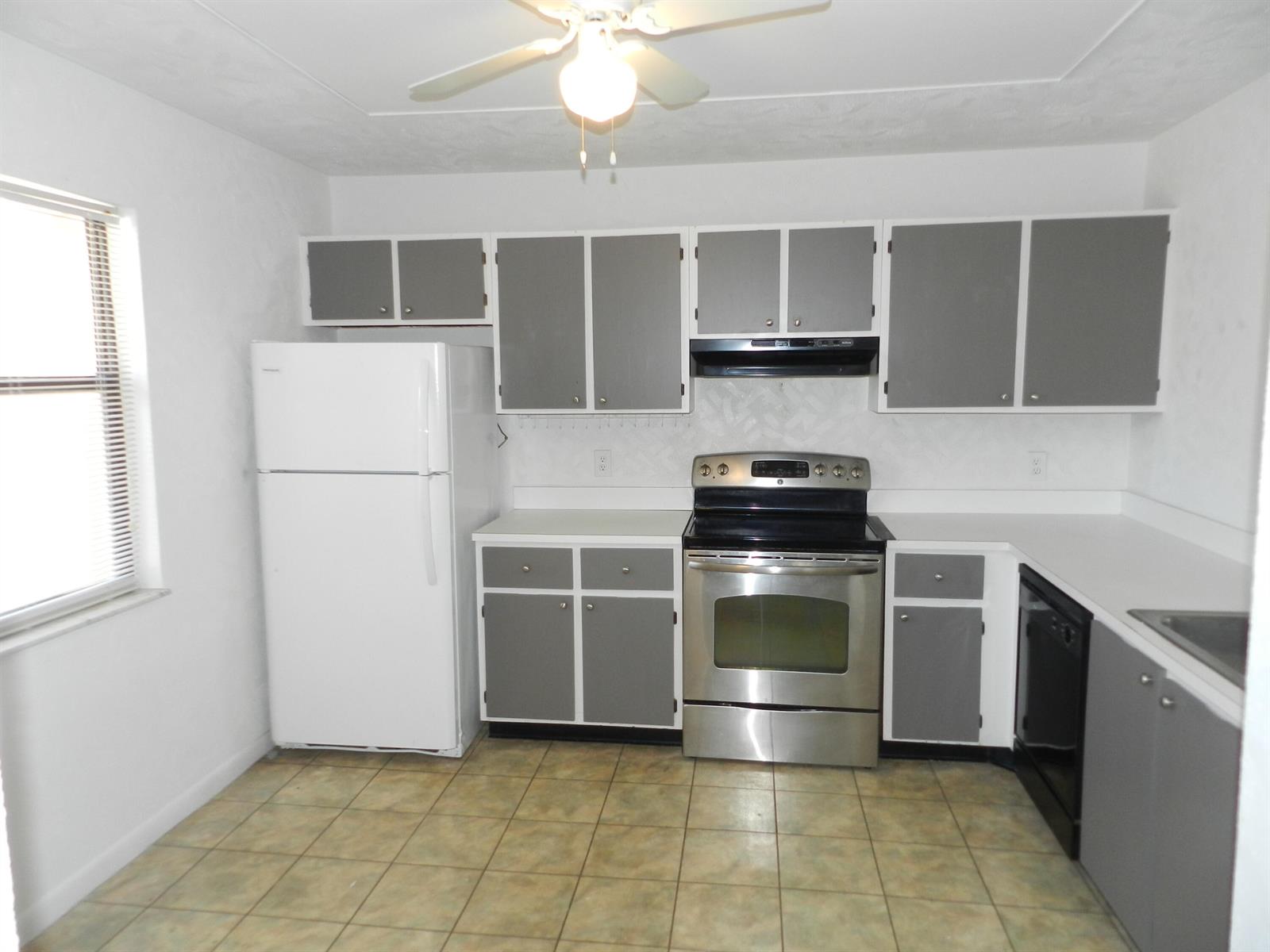 A kitchen features gray cabinets, white countertops, stainless steel appliances, and a tiled floor — 1110 E Lakeview Dr Drive E, Royal Palm Beach FL 33411, ROYAL PALM BEACH, FL