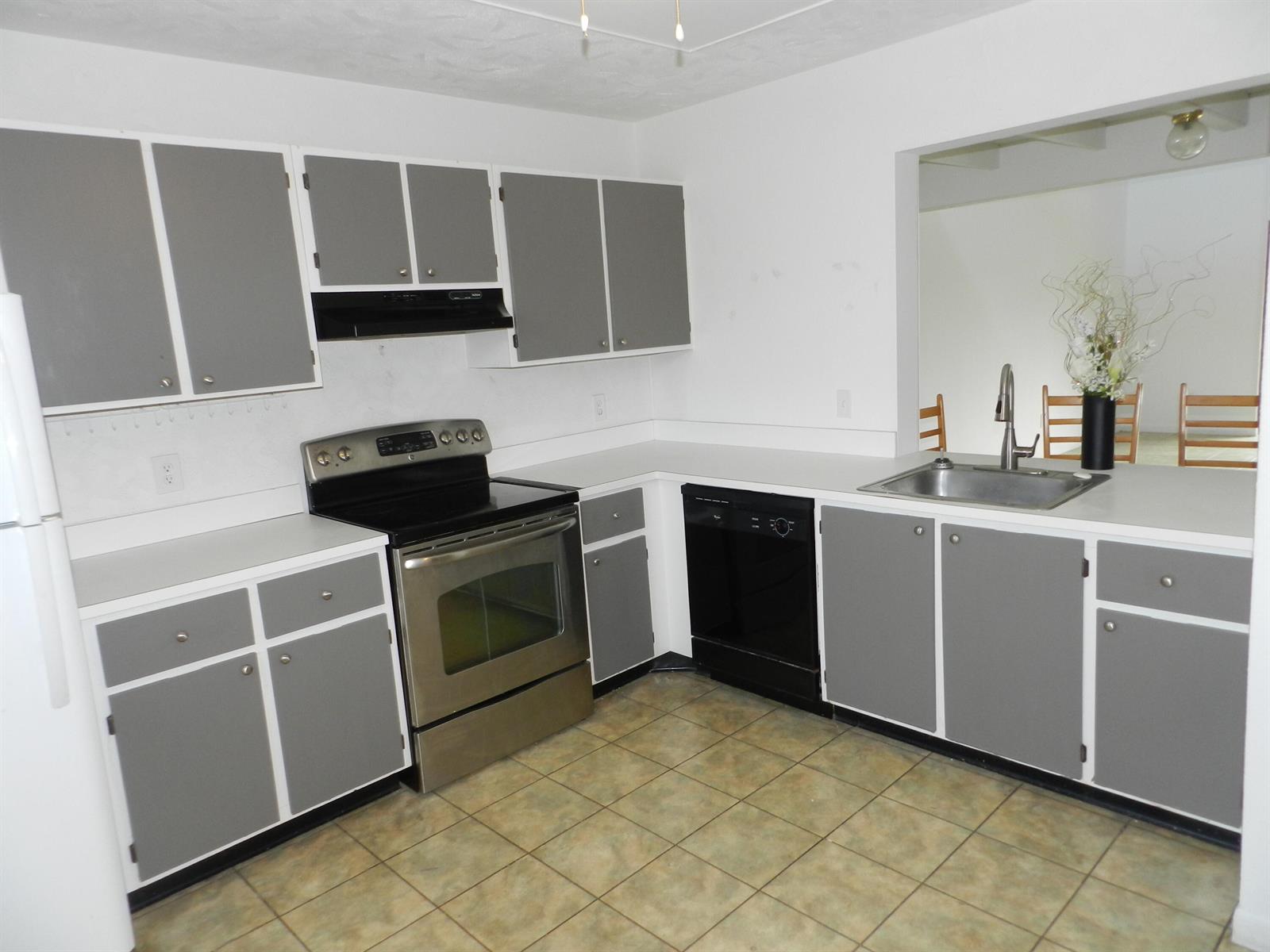 A kitchen features gray cabinets, white countertops, stainless steel appliances, and tiled flooring — 1110 E Lakeview Dr Drive E, Royal Palm Beach FL 33411, ROYAL PALM BEACH, FL