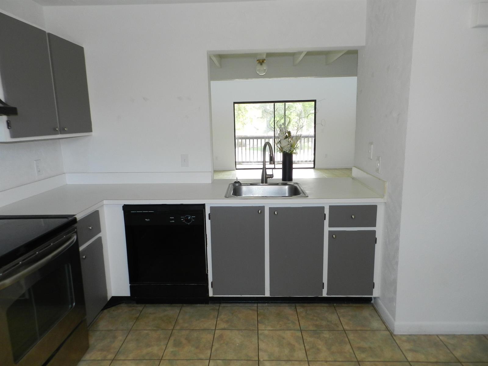 A kitchen features gray cabinets, a black dishwasher, stainless steel appliances, and a pass-through window — 1110 E Lakeview Dr Drive E, Royal Palm Beach FL 33411, ROYAL PALM BEACH, FL