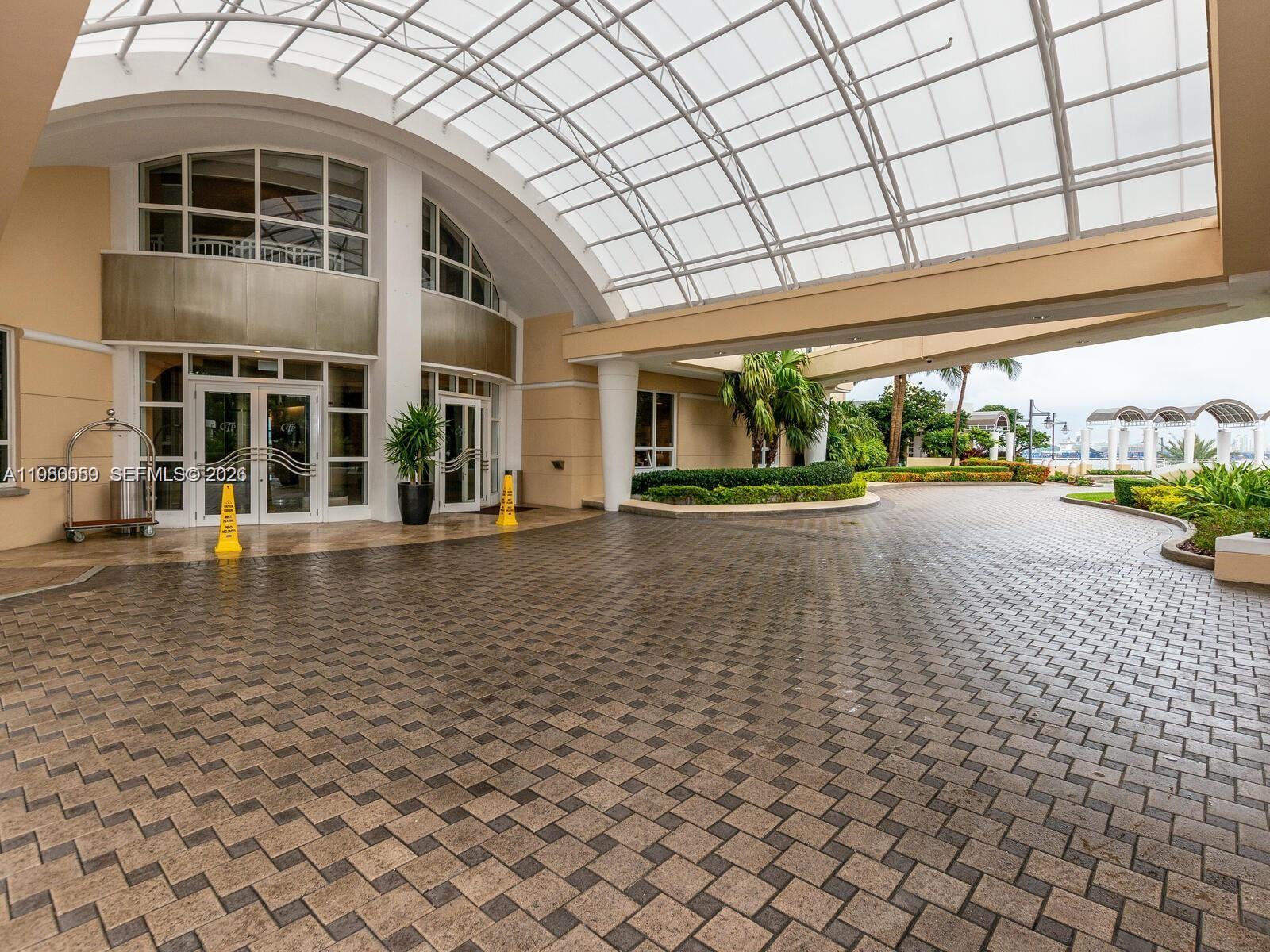 A paved driveway leads to a building entrance covered by a large, arched glass canopy — 848 Brickell Key Dr # 1201, Miami FL 33131, MIAMI, FL