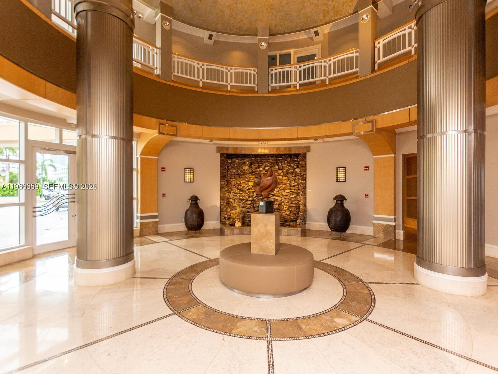 A circular lobby features two large metallic columns, a stone accent wall, and a central sculpture — 848 Brickell Key Dr # 1201, Miami FL 33131, MIAMI, FL