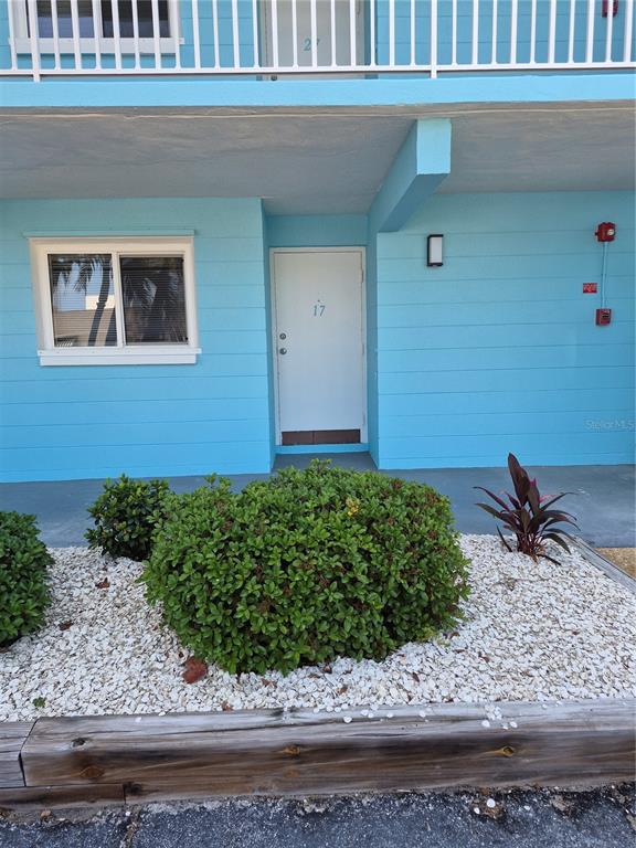 A blue exterior wall features a white door labeled 17, a window, and landscaping — 1505 PASS A GRILLE WAY UNIT 17, ST PETE BEACH, FL