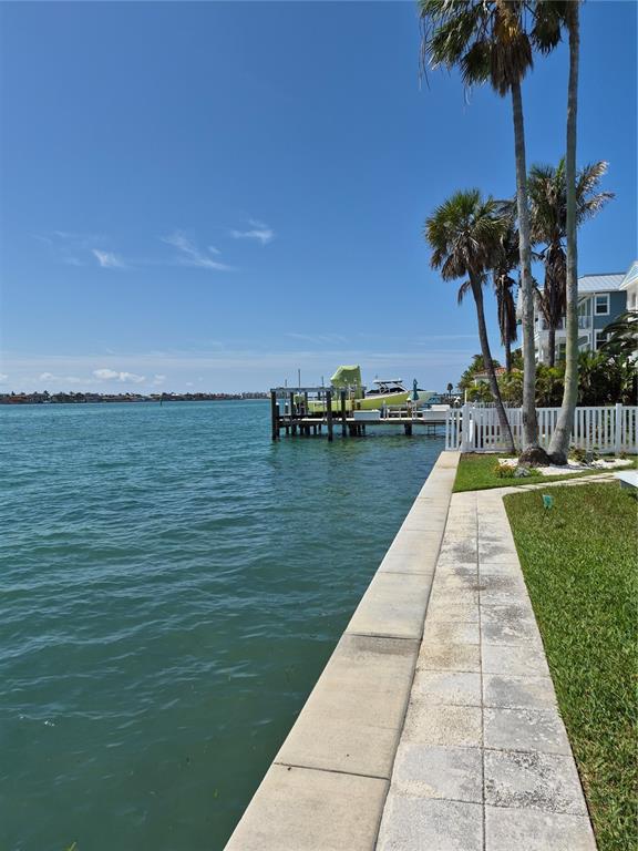 A paved walkway runs alongside a waterfront seawall with a private dock and boat — 1505 PASS A GRILLE WAY UNIT 17, ST PETE BEACH, FL