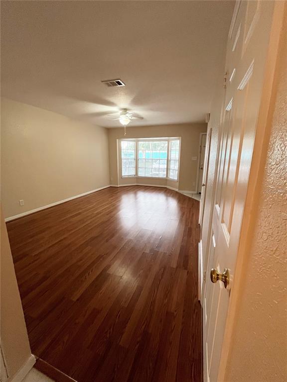 An empty living room features wood-look flooring, a ceiling fan, and a bay window — 37240 EMBASSY PARK LANE, DADE CITY, FL