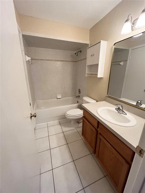 A bathroom features a white bathtub, a toilet, a wooden vanity, and a wall-mounted cabinet — 37240 EMBASSY PARK LANE, DADE CITY, FL