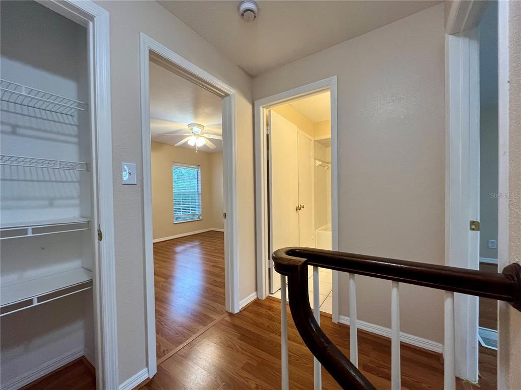 A hallway with wood flooring leads to a bedroom and a bathroom with white walls — 37240 EMBASSY PARK LANE, DADE CITY, FL