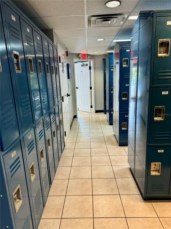 A narrow hallway features rows of blue metal lockers on both sides and tiled flooring — 1780 PHILLIPPI SHORES DRIVE UNIT C1-14, SARASOTA, FL