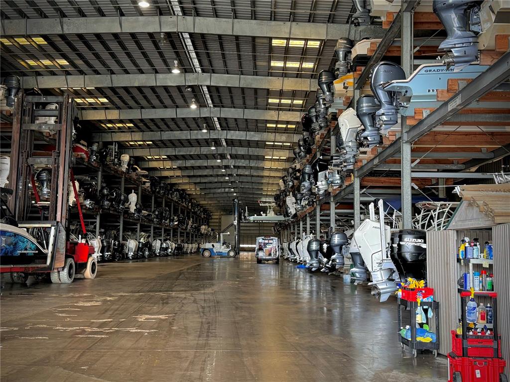 A large industrial warehouse storage facility features rows of stacked boats and outboard motors — 1780 PHILLIPPI SHORES DRIVE UNIT C1-14, SARASOTA, FL