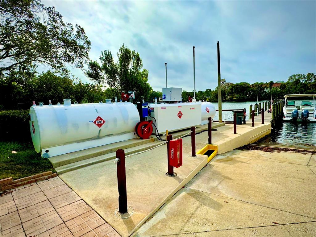 A fuel tank station sits on a concrete dock next to a boat in the water — 1780 PHILLIPPI SHORES DRIVE UNIT C1-14, SARASOTA, FL