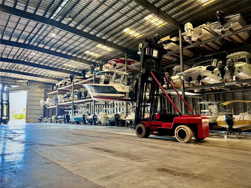 A large indoor boat storage facility features stacked racks and a red forklift — 1780 PHILLIPPI SHORES DRIVE UNIT C1-14, SARASOTA, FL