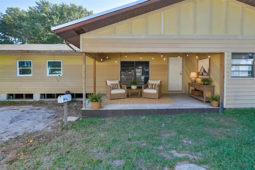 A single-story house features a covered front porch with wicker chairs and string lights — 741 MORREL AVENUE, LAKE WALES, FL