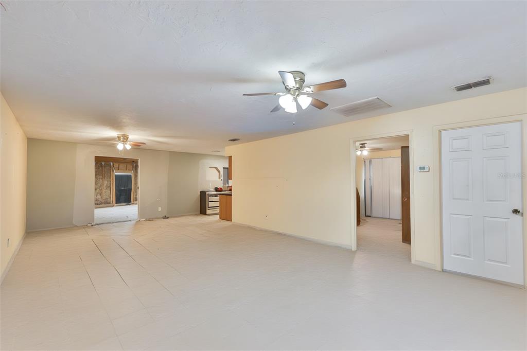A spacious room with light-colored tile flooring, yellow walls, and two ceiling fans — 741 MORREL AVENUE, LAKE WALES, FL