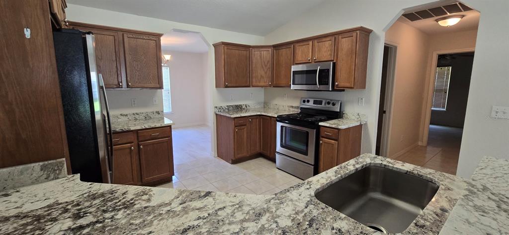A kitchen features wood cabinets, granite countertops, and stainless steel appliances — 113 TEAK ROAD, OCALA, FL