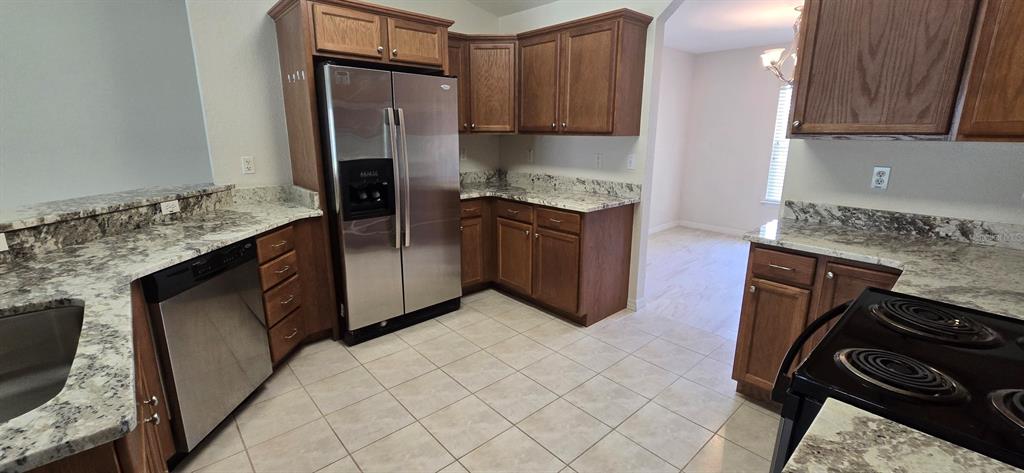 A kitchen features wood cabinets, granite countertops, stainless steel appliances, and tile flooring — 113 TEAK ROAD, OCALA, FL