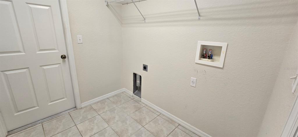 A laundry room features tile flooring, a white door, and wall-mounted utility connections — 113 TEAK ROAD, OCALA, FL