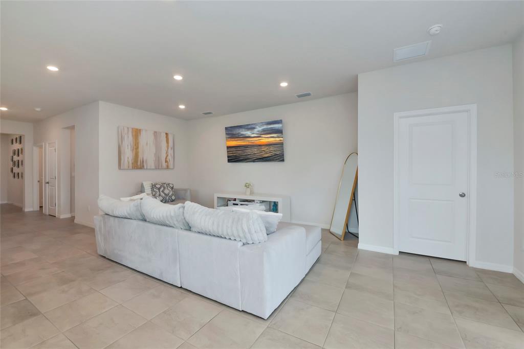 A living room features a light gray sectional sofa, a television, and tile flooring — 627 160TH STREET E, BRADENTON, FL