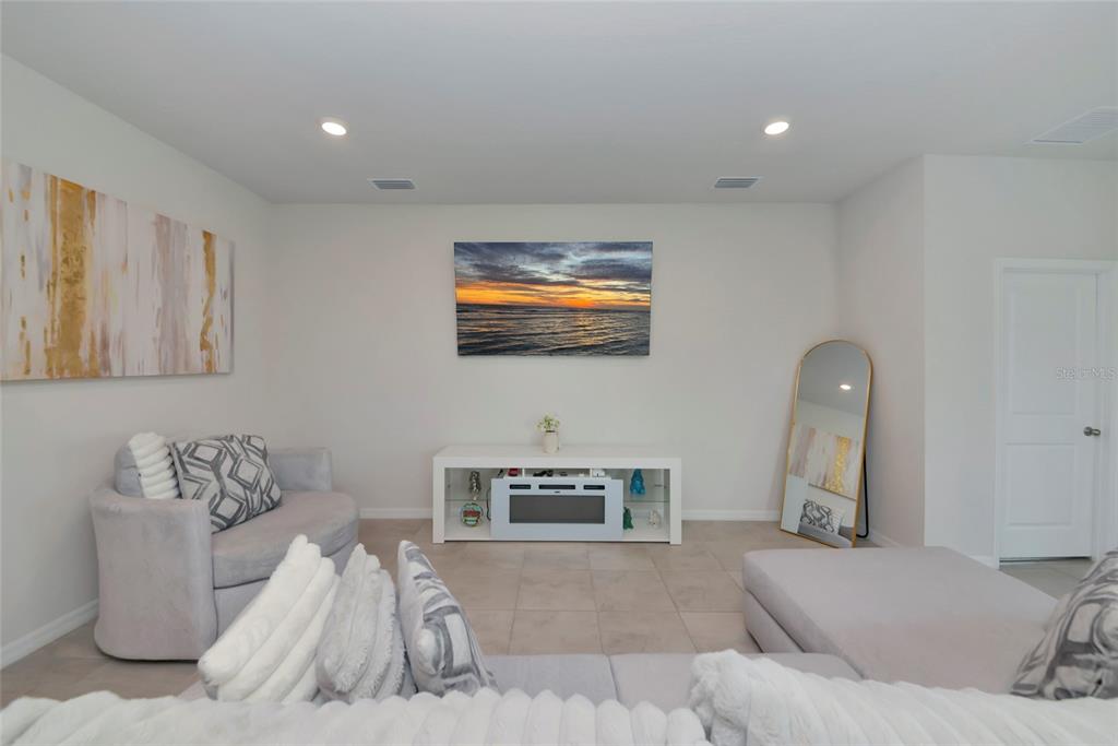 A living room features a white media console, a wall-mounted television, and light-colored furniture — 627 160TH STREET E, BRADENTON, FL