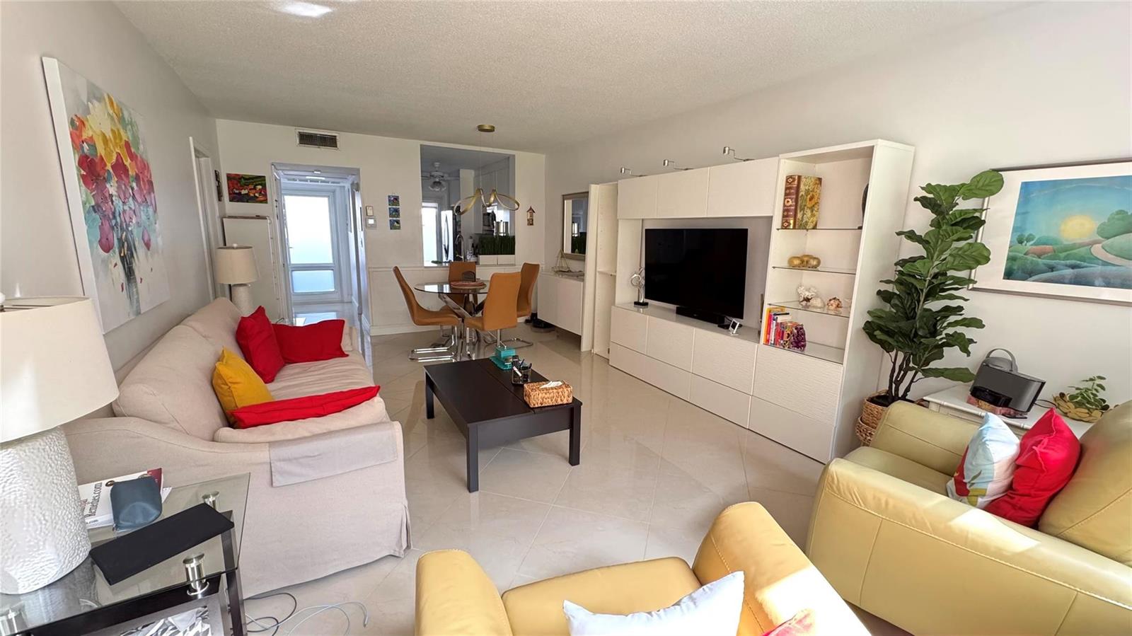 A living room features a beige sofa, yellow armchairs, a television unit, and tile flooring — 1481 S Ocean Boulevard # 124, Pompano Beach FL 33062, POMPANO BEACH, FL
