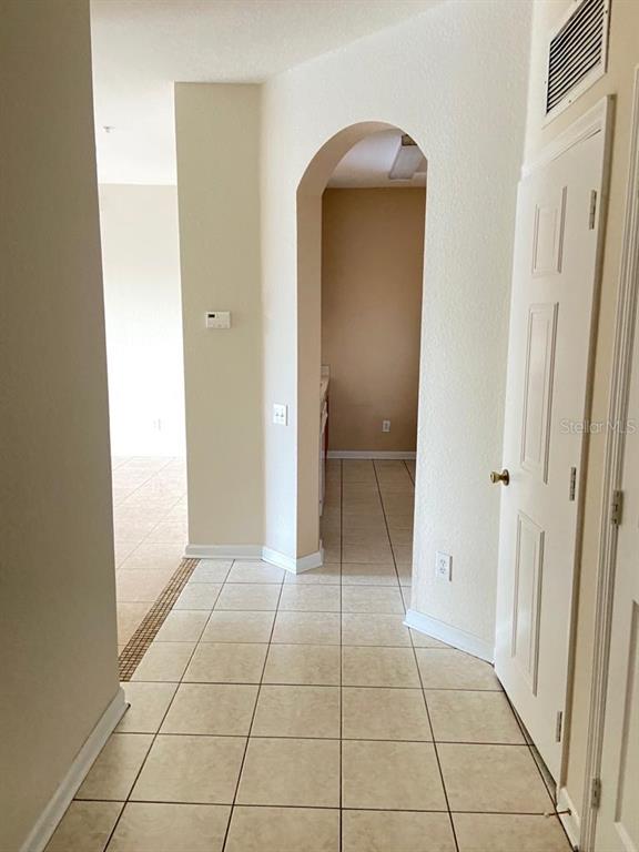 A tiled hallway leads through an arched doorway toward a room with light-colored walls — 6100 STEVENSON DRIVE UNIT 208, ORLANDO, FL