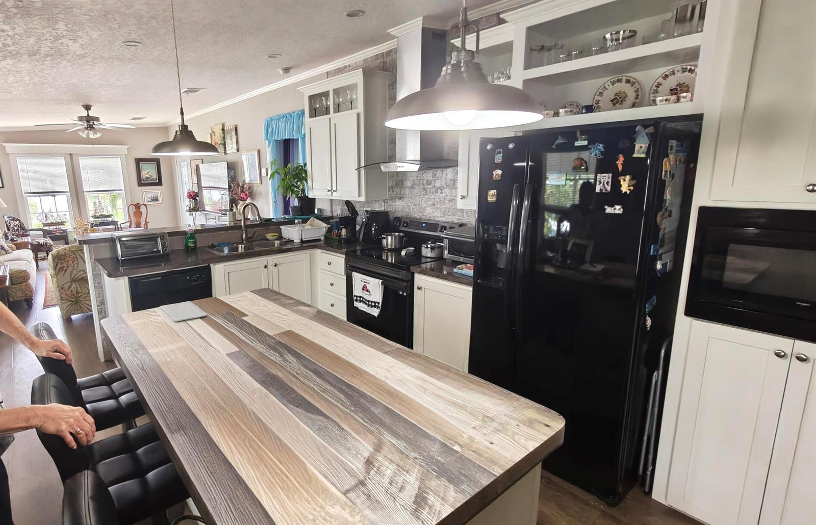 A kitchen features a wood-topped island, white cabinets, black appliances, and a brick-patterned backsplash — 7306 43rd Terrace N, Riviera Beach FL 33404, RIVIERA BEACH, FL