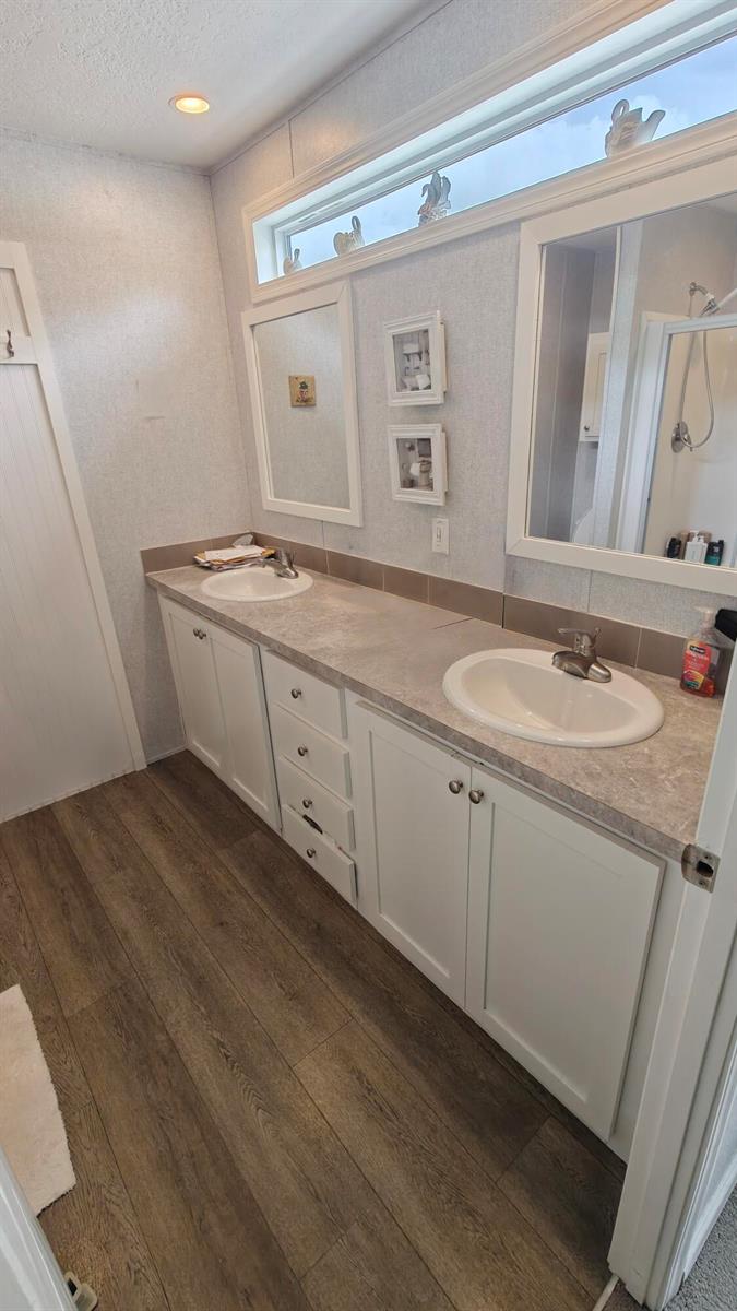 A bathroom features a double vanity with white cabinets, a gray countertop, and wood-look flooring — 7306 43rd Terrace N, Riviera Beach FL 33404, RIVIERA BEACH, FL