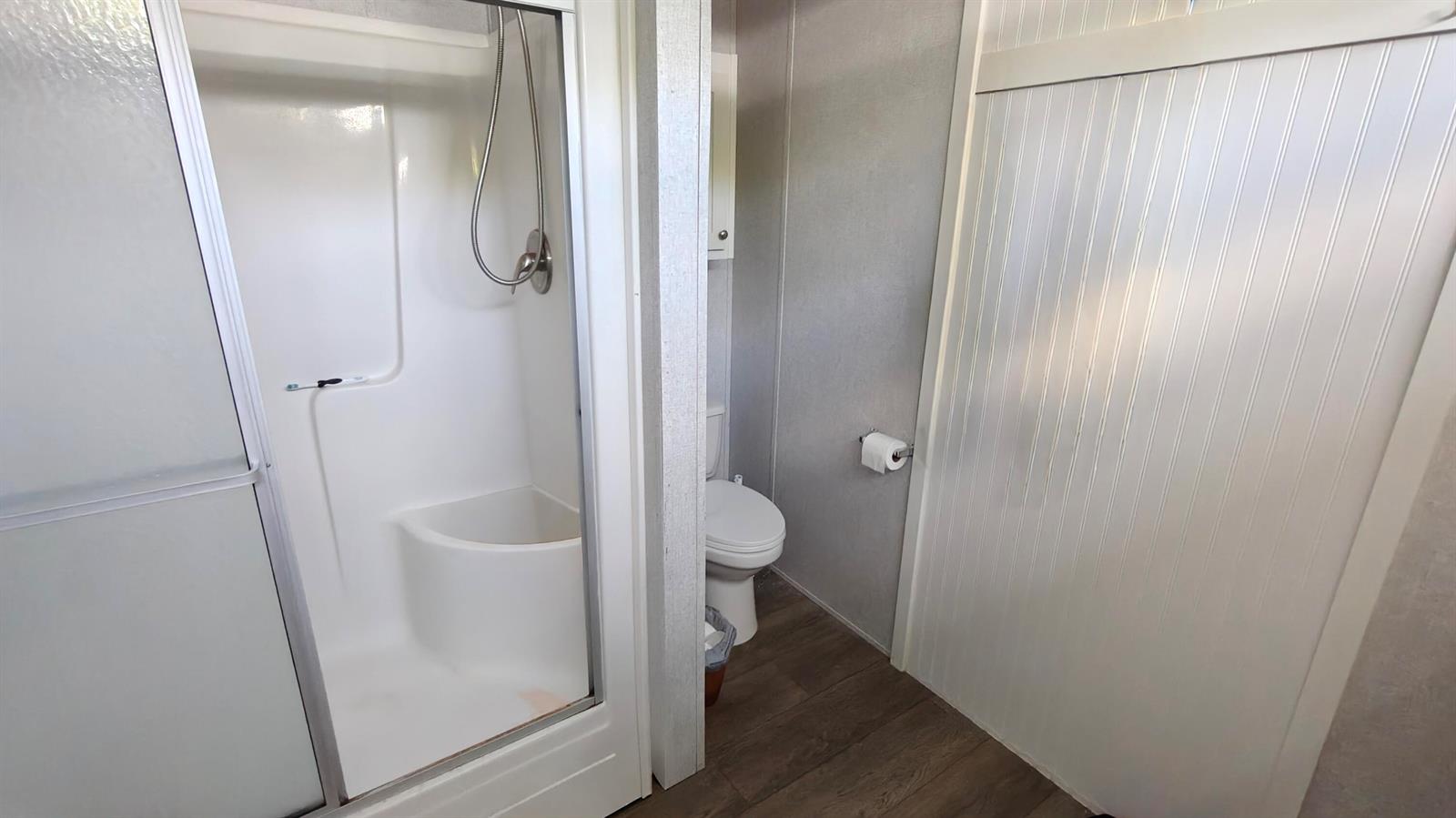 A bathroom features a walk-in shower with a built-in seat and a white toilet — 7306 43rd Terrace N, Riviera Beach FL 33404, RIVIERA BEACH, FL
