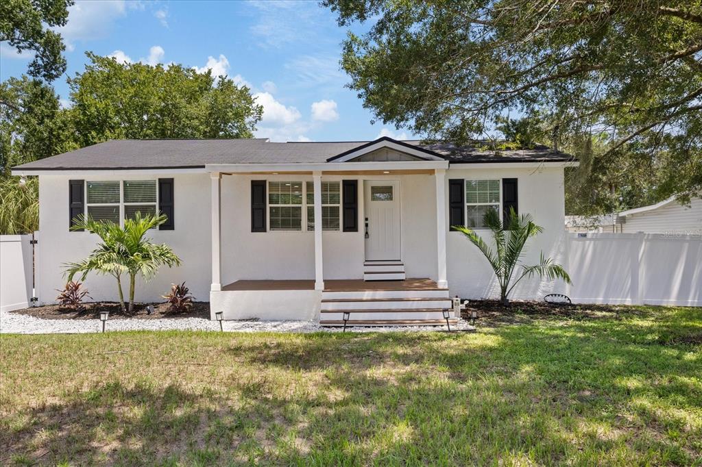 A white single-story house with black shutters, a covered front porch, and a grassy yard — 6403 ELLIOT DRIVE, TAMPA, FL