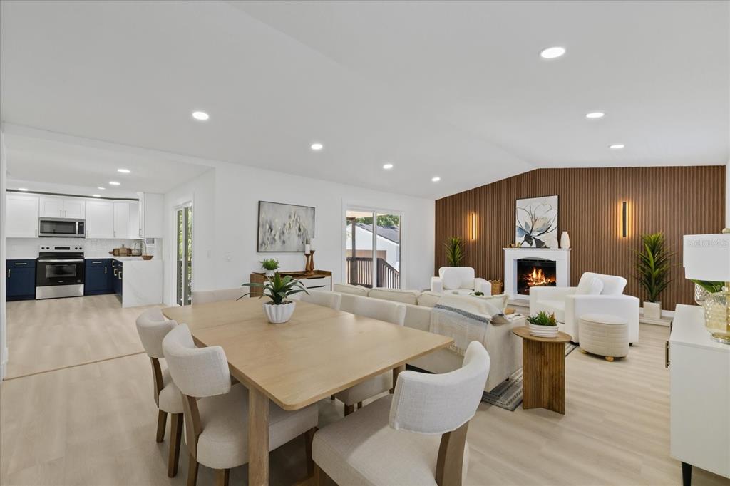 An open-concept living and dining area features a fireplace with a wood-slat accent wall — 6403 ELLIOT DRIVE, TAMPA, FL