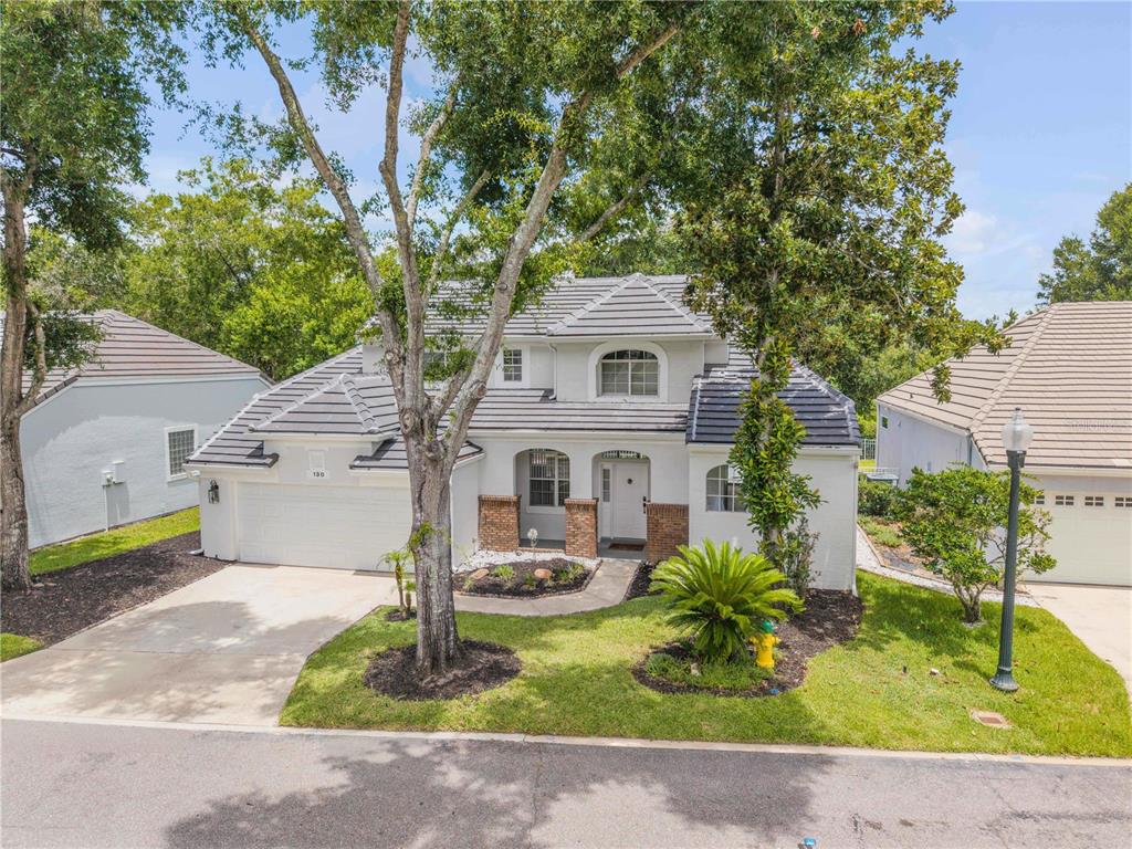 A two-story white house with a dark tile roof and a front-facing garage — 130 WIMBLEDON CIRCLE, LAKE MARY, FL