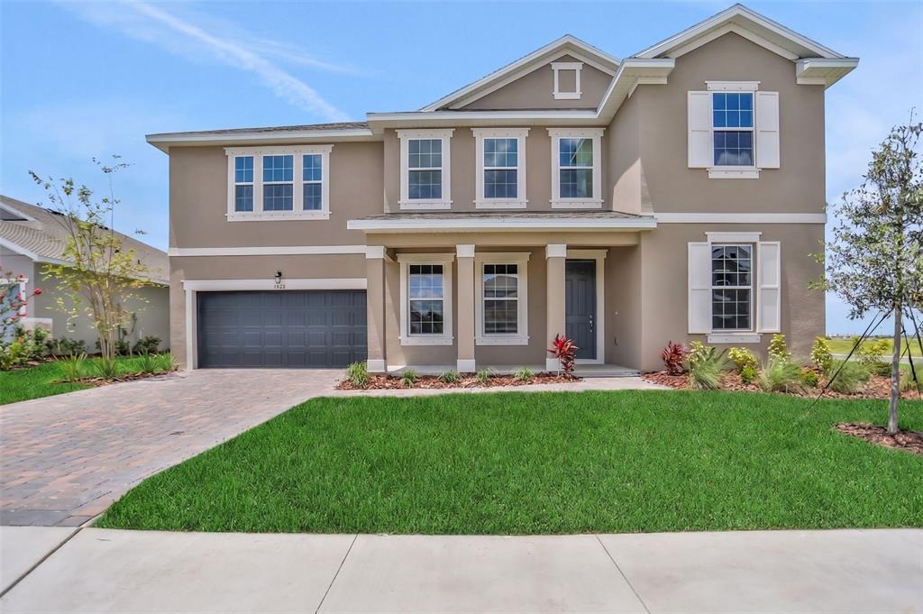 A two-story suburban house with a gray garage, beige stucco exterior, and a front lawn — 7422 SEA MANATEE STREET, PARRISH, FL
