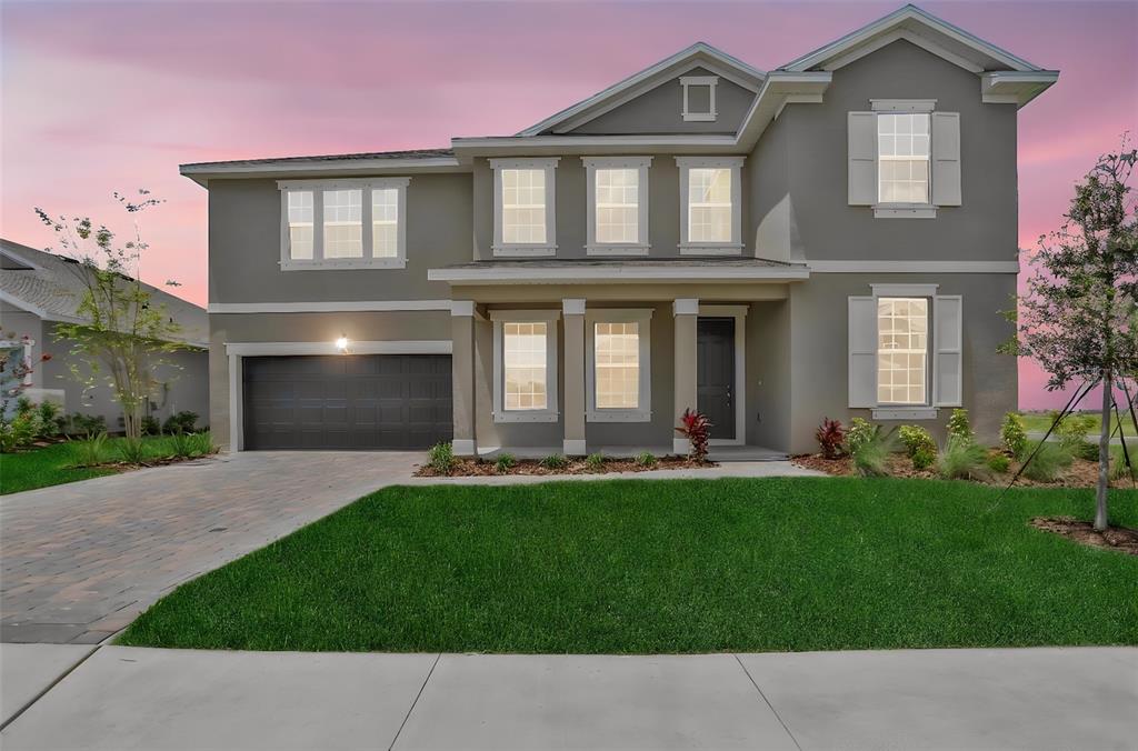 A two-story gray house with a two-car garage and a front lawn at sunset — 7422 SEA MANATEE STREET, PARRISH, FL