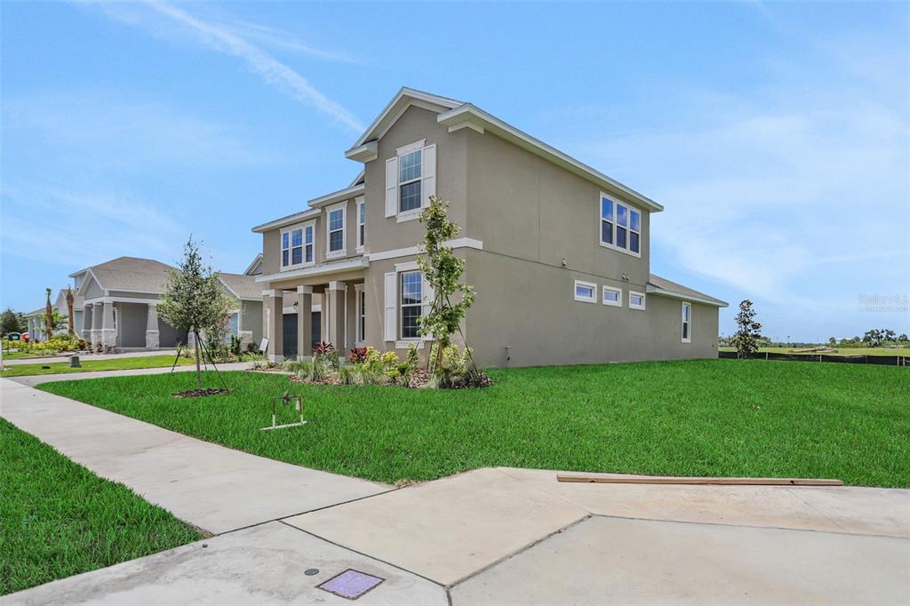 A two-story suburban house with a tan stucco exterior and a green lawn — 7422 SEA MANATEE STREET, PARRISH, FL