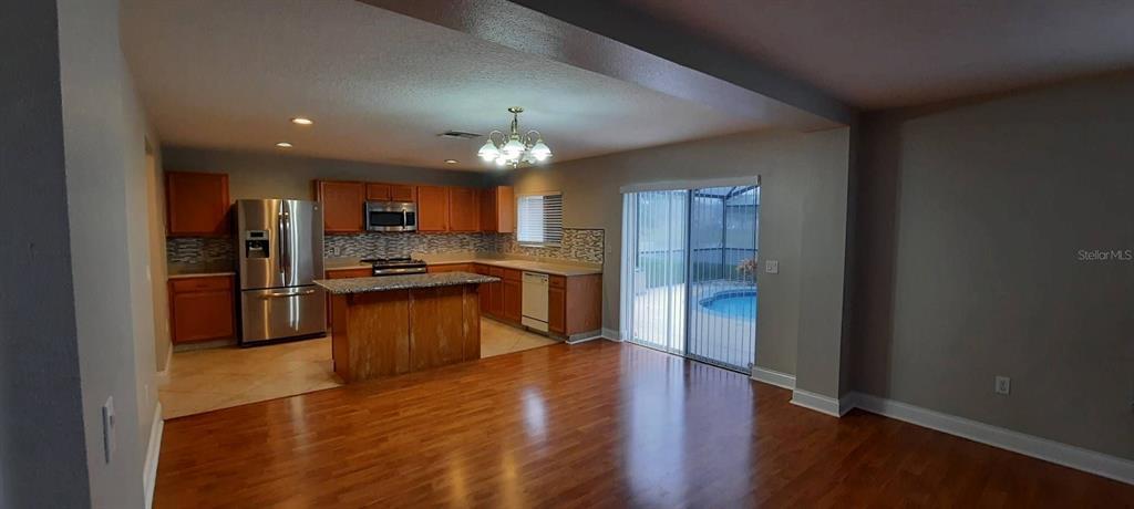 A screened-in swimming pool overlooks a lake and grassy backyard with trees — 12827 OULTON CIRCLE, ORLANDO, FL