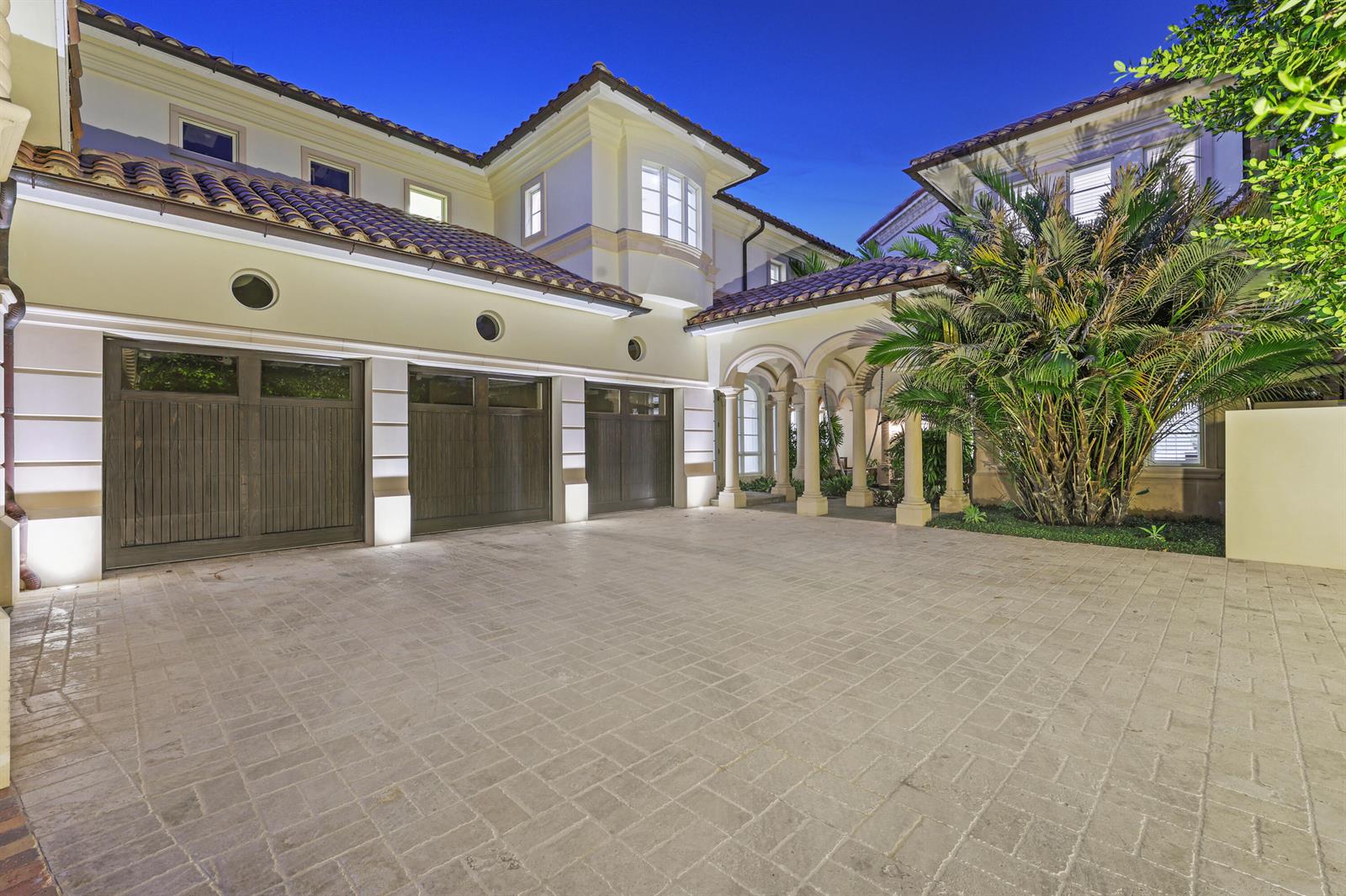 A paved driveway leads to a three-car garage and a covered entrance with stone columns — 361 Mizner Lake Estates Drive, Boca Raton FL 33432, BOCA RATON, FL