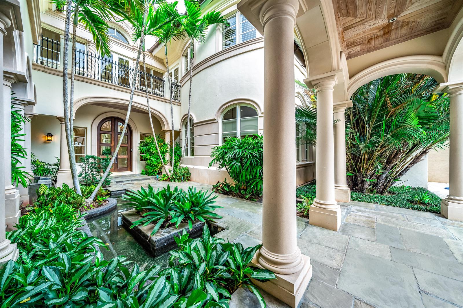 A courtyard features a stone patio, a small reflecting pool, lush plants, and arched architecture — 361 Mizner Lake Estates Drive, Boca Raton FL 33432, BOCA RATON, FL