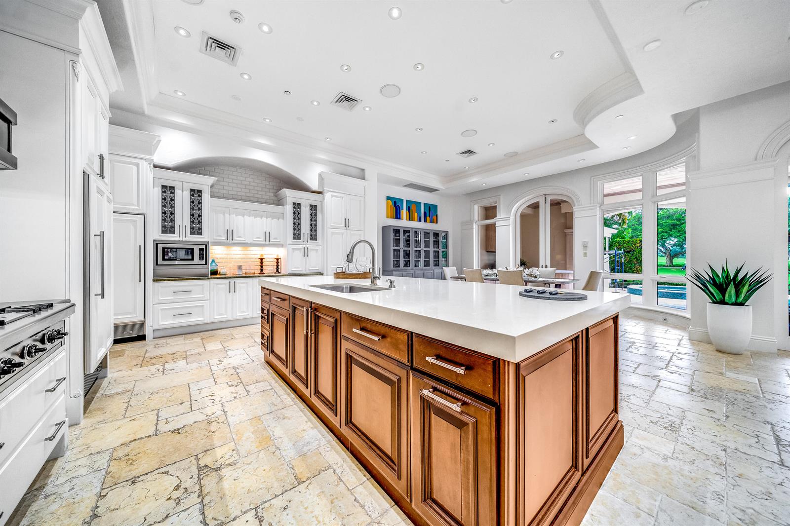 A spacious kitchen features a large wooden island, white cabinetry, and stone tile flooring — 361 Mizner Lake Estates Drive, Boca Raton FL 33432, BOCA RATON, FL