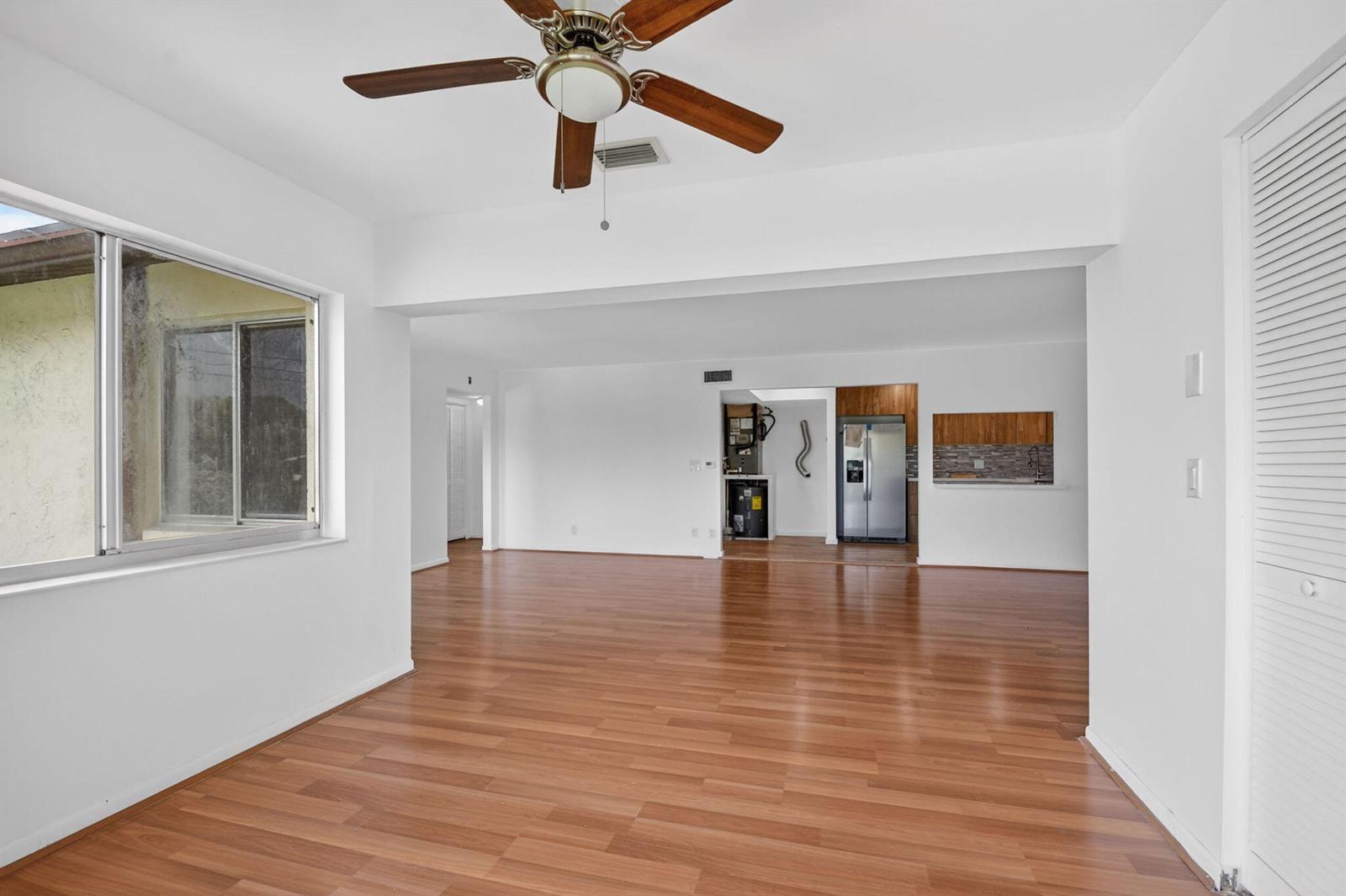 An open-concept living area features wood-look flooring, a ceiling fan, and a view into the kitchen — 4991 Sable Pine Circle # C2, West Palm Beach FL 33417, WEST PALM BEACH, FL