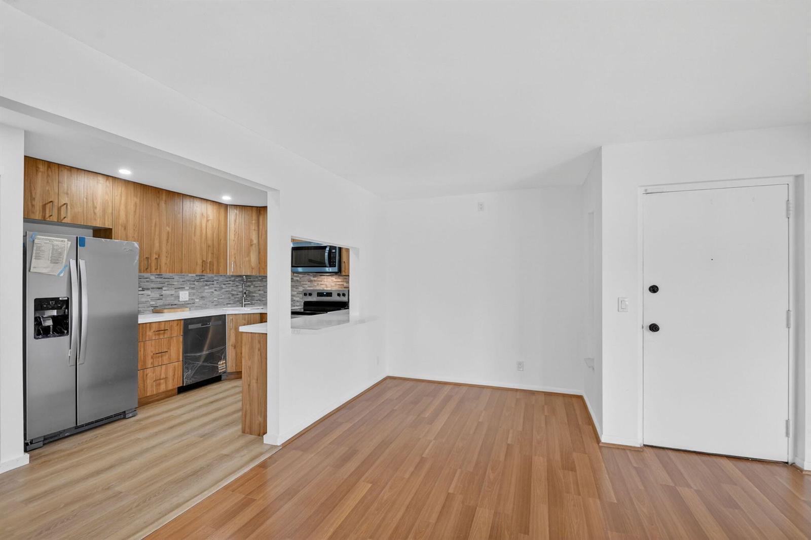 A kitchen with wood cabinets and stainless steel appliances opens into a dining area — 4991 Sable Pine Circle # C2, West Palm Beach FL 33417, WEST PALM BEACH, FL
