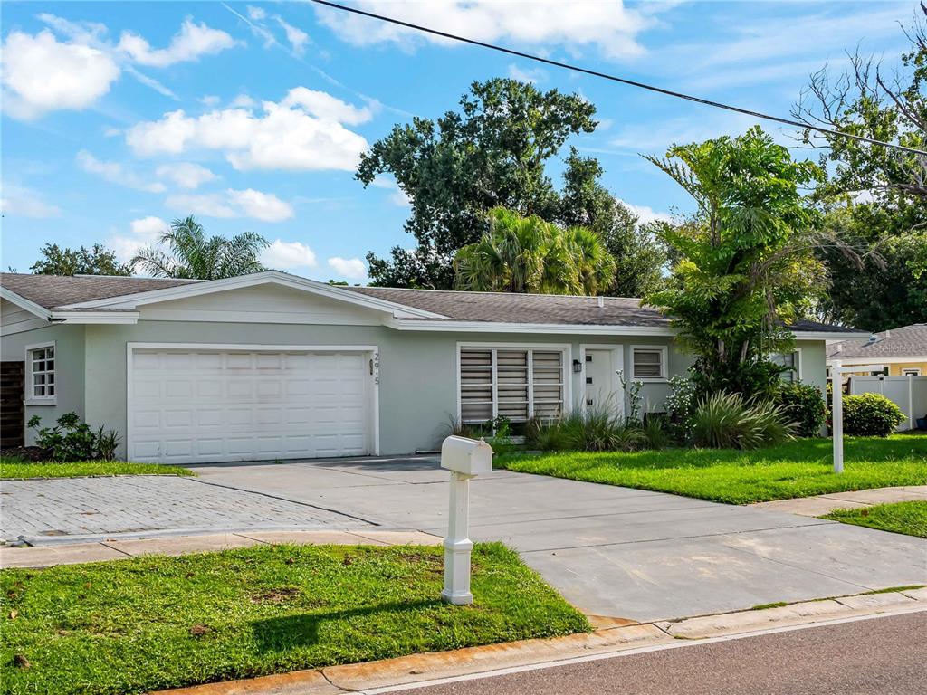 A single-story house with a light green exterior, a two-car garage, and a concrete driveway — 2915 WEBBER STREET, SARASOTA, FL