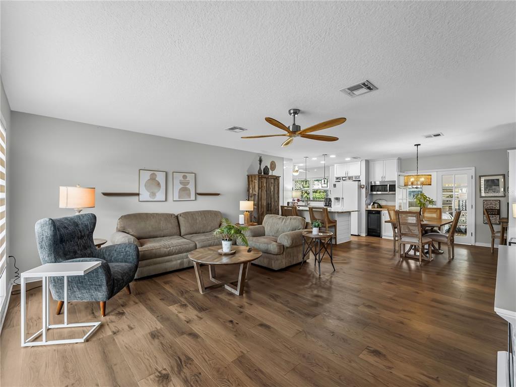 An open-concept living room and kitchen featuring hardwood floors, a ceiling fan, and neutral walls — 2915 WEBBER STREET, SARASOTA, FL