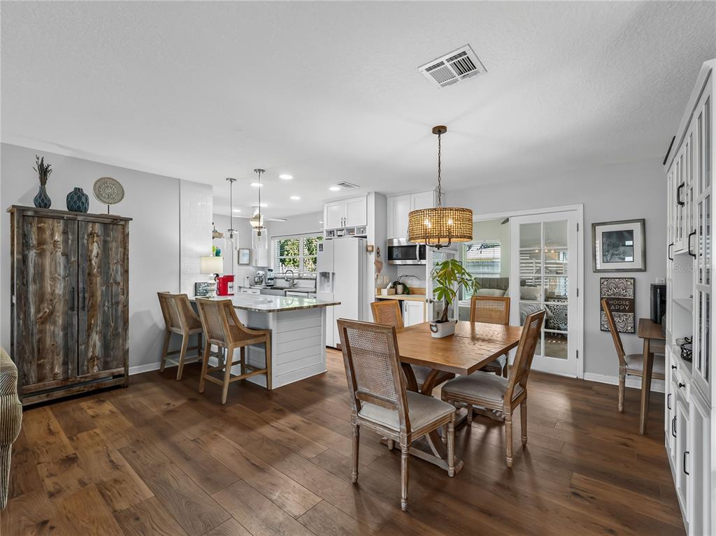 A kitchen and dining area with wood floors, a center island, and a wooden table — 2915 WEBBER STREET, SARASOTA, FL