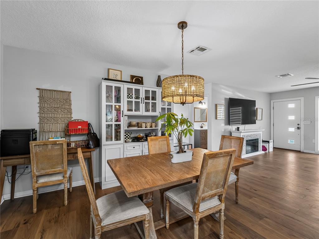 A dining room features a wooden table, cane-back chairs, a hutch, and a pendant light — 2915 WEBBER STREET, SARASOTA, FL
