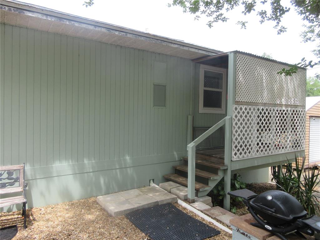The exterior of a light green home features a wooden deck with white lattice railings — 5949 SE 164TH COURT, OCKLAWAHA, FL