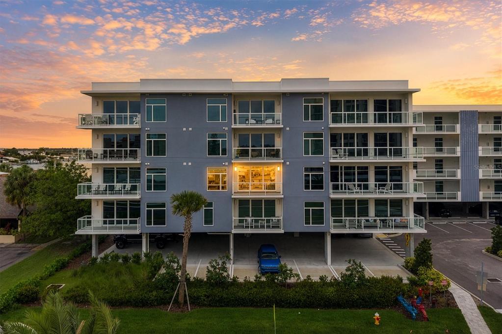 An exterior view of a modern multi-story apartment building with balconies and ground-level parking — 415 ISLAND WAY UNIT 311, CLEARWATER BEACH, FL