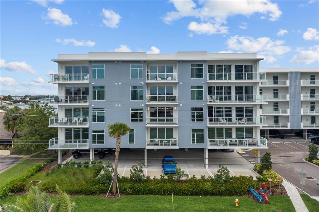 An exterior view of a modern multi-story apartment building with balconies and covered parking — 415 ISLAND WAY UNIT 311, CLEARWATER BEACH, FL