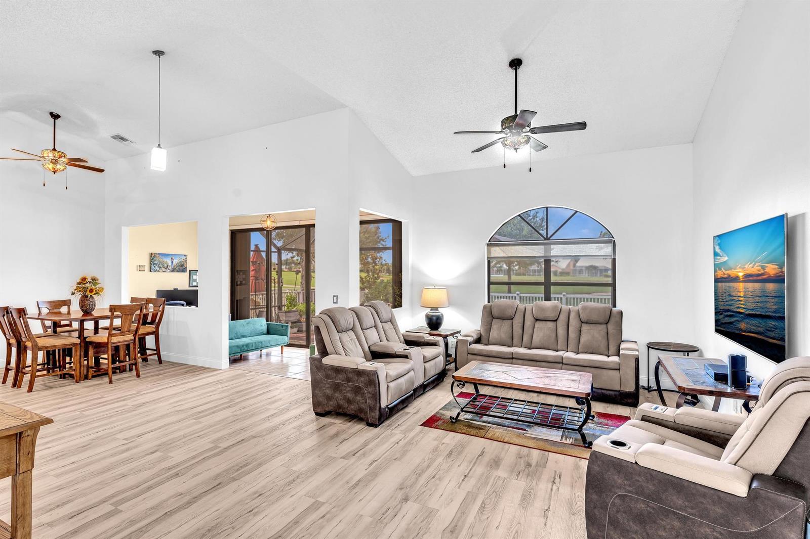 A living room with light wood floors, vaulted ceilings, and a view of a patio — 8099 Cassia Drive, Boynton Beach FL 33472, BOYNTON BEACH, FL