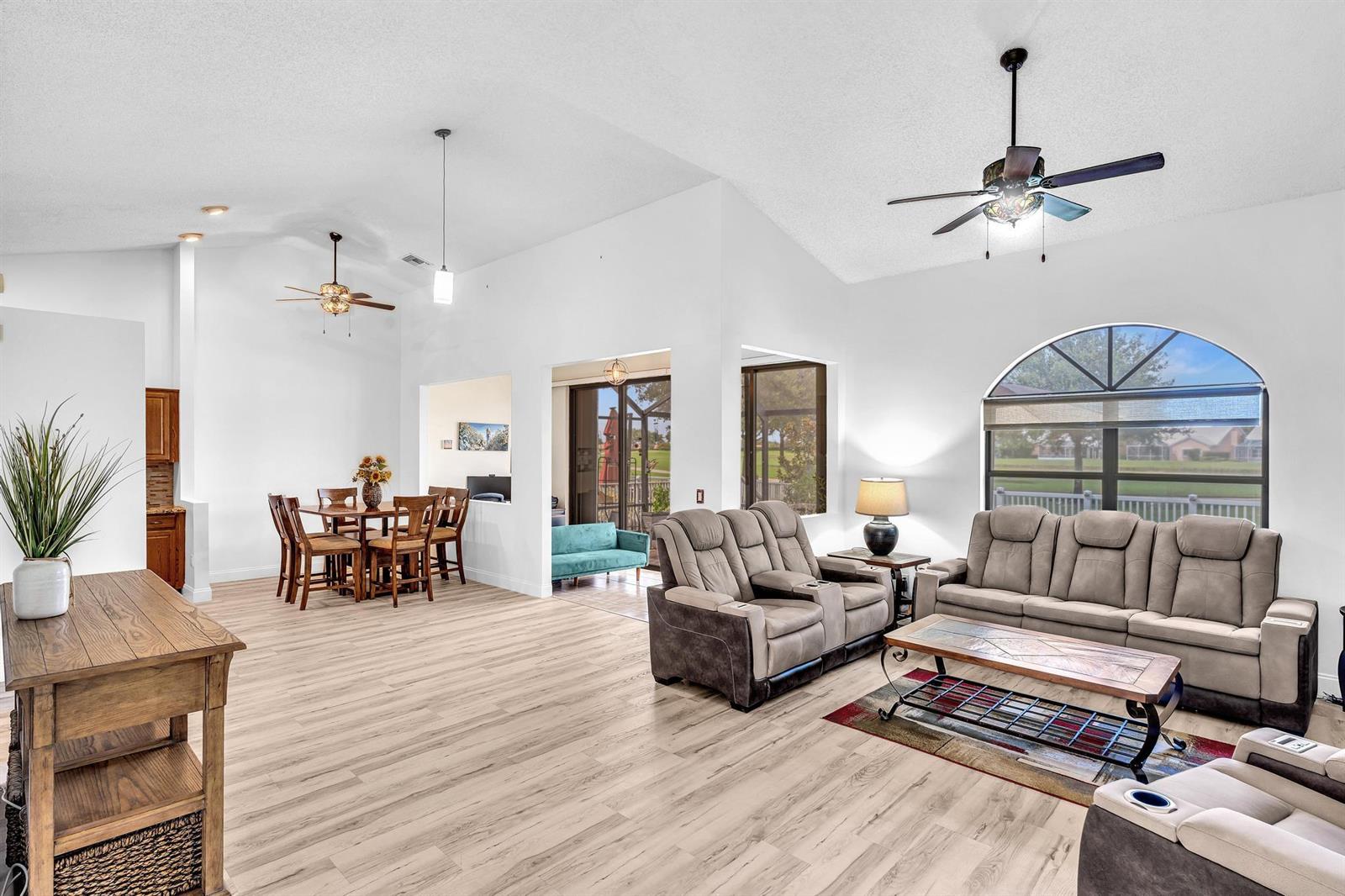 A bright living and dining area with vaulted ceilings, light wood floors, and patio access — 8099 Cassia Drive, Boynton Beach FL 33472, BOYNTON BEACH, FL